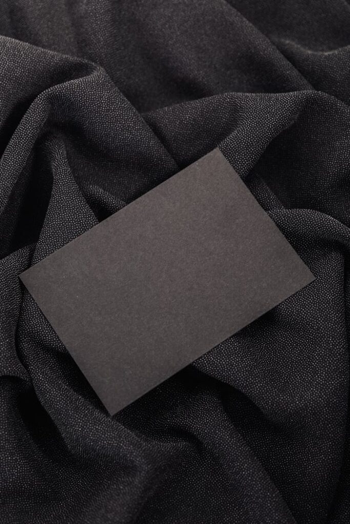The Art of Drawing Readers In: Your attractive post title goes here Black card on textured black fabric background, ideal for mockups and design presentations.
