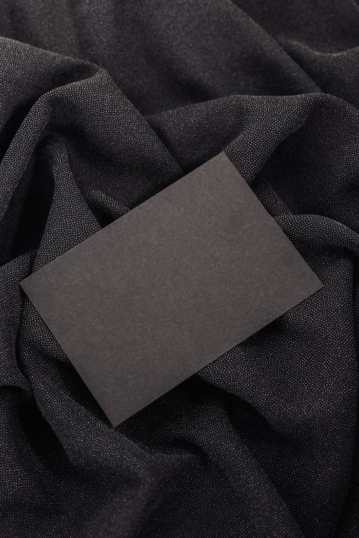 Black card on textured black fabric background, ideal for mockups and design presentations.